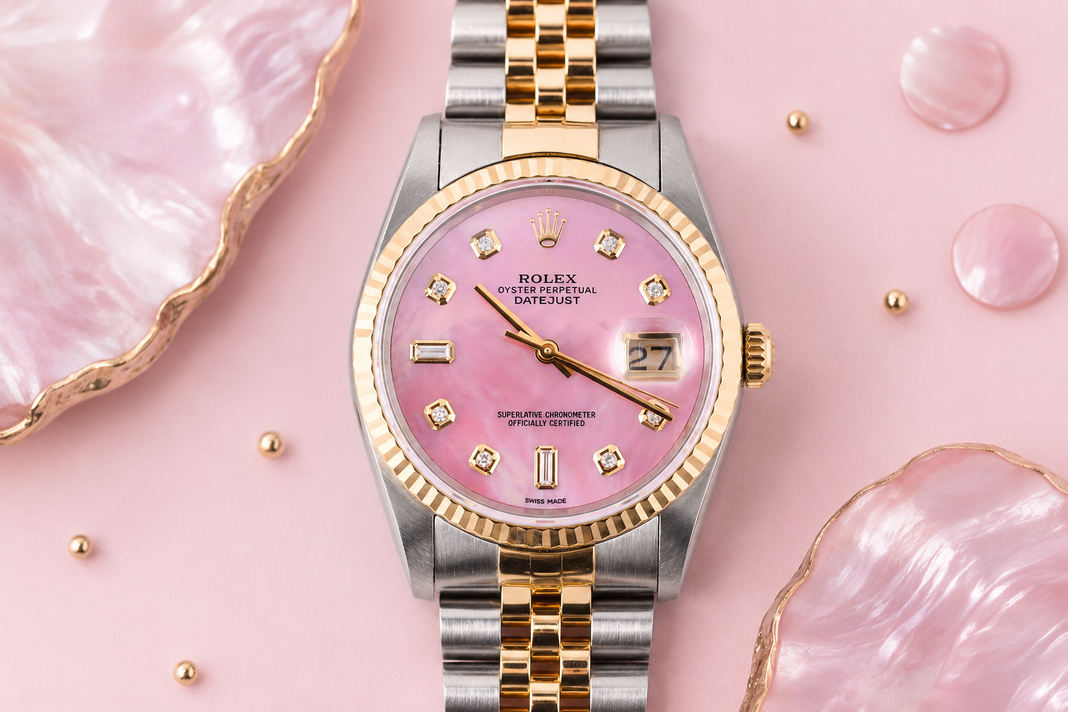 Luxury watch with pink dial and gold accents on a pink textured background