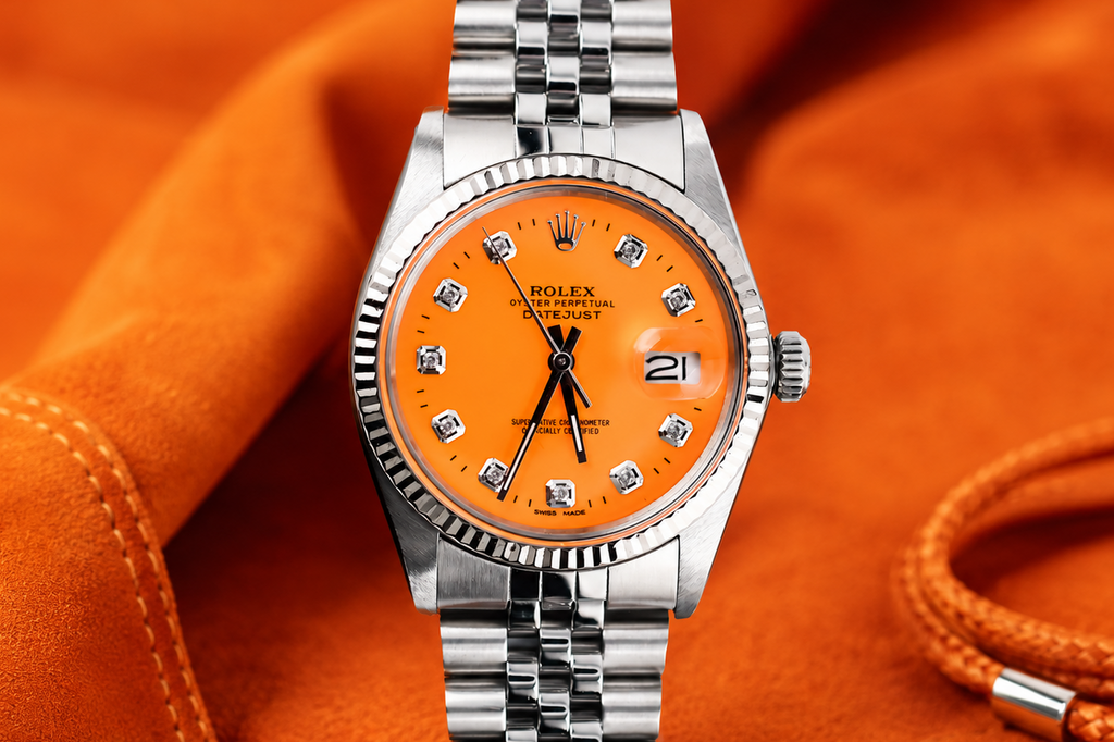 Silver watch with an orange face on an orange fabric background