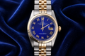 Luxury watch with blue face and gold accents on a blue fabric background