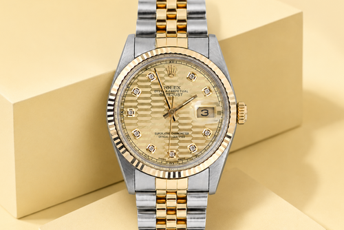 Luxury watch with gold and silver band on a beige geometric background