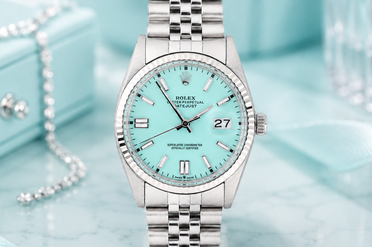 Silver watch with a turquoise face on a light blue background