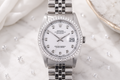 Silver watch with diamond-studded bezel on a marble surface