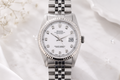 Silver watch with a white face on a white background