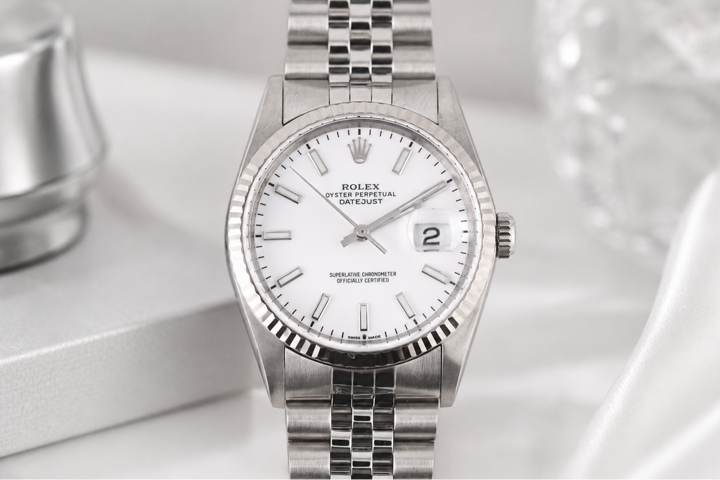 Silver watch with a white face on a light gray background