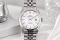 Silver watch with a white face on a light gray background
