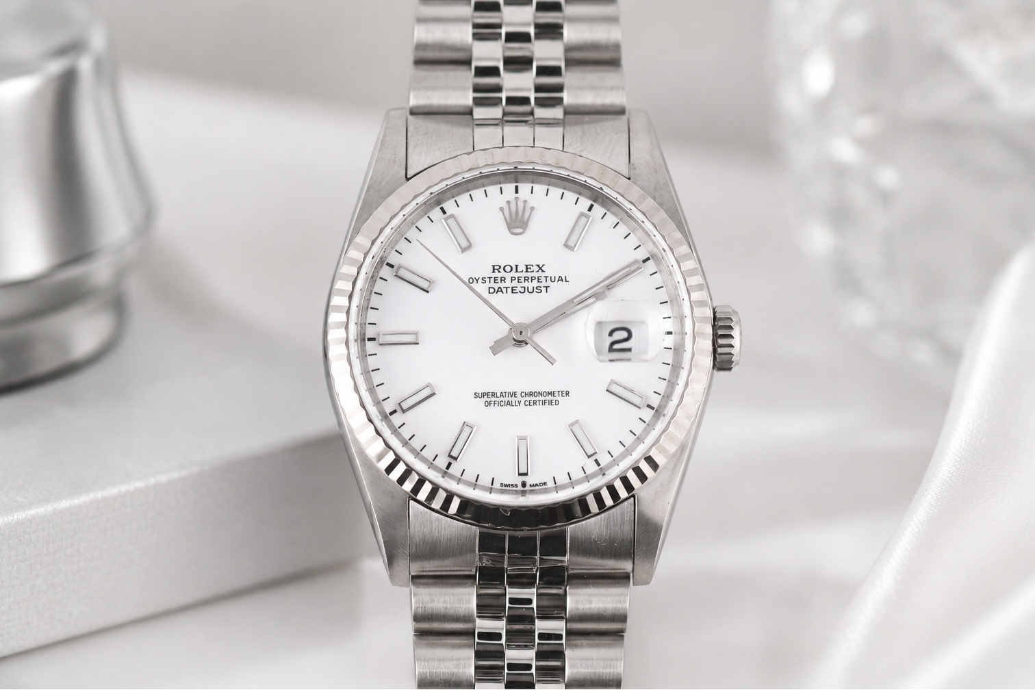 Silver watch with a white face on a light gray background