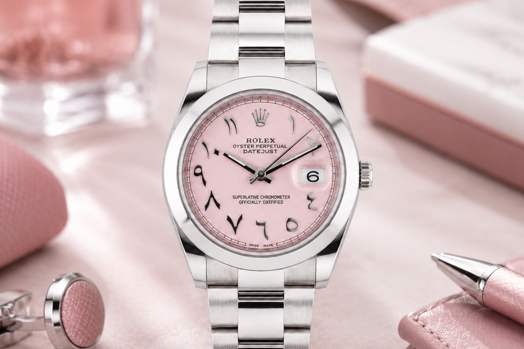 Silver watch with pink face on a pink surface with accessories