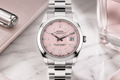 Silver watch with a pink face on a marble surface