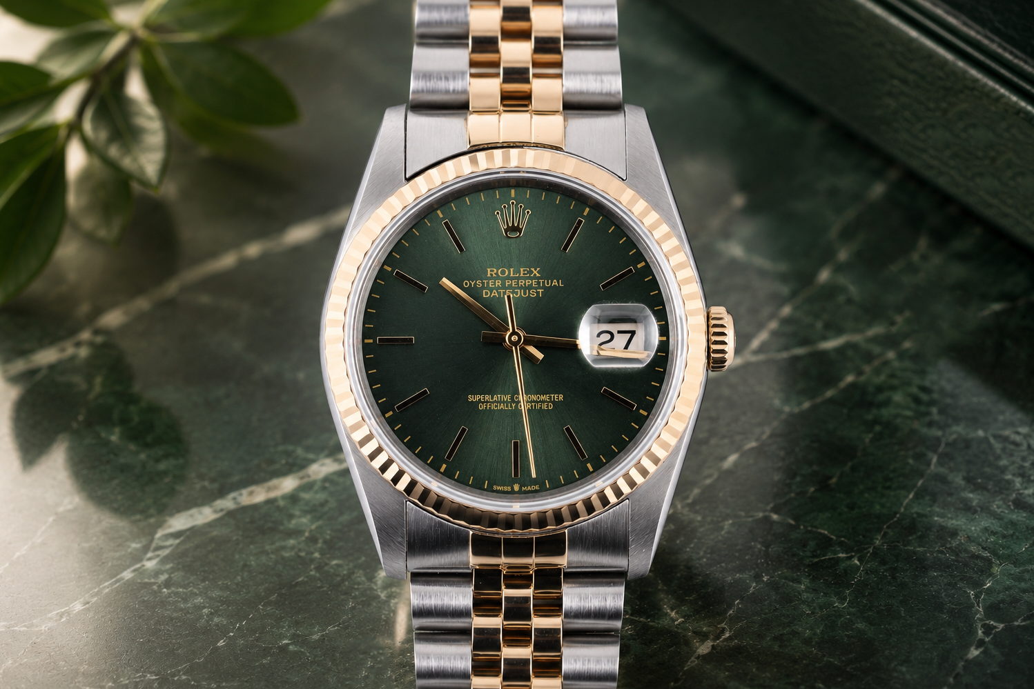 Luxury watch with green dial and gold accents on a marble surface