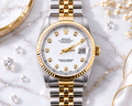 Gold and silver watch with diamond accents on a marble surface