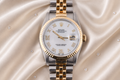 Luxury watch with silver and gold band on a soft fabric background