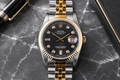 Luxury watch with black dial and gold accents on a marble surface
