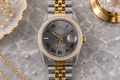 Luxury watch with gold and silver band on a gray marble surface