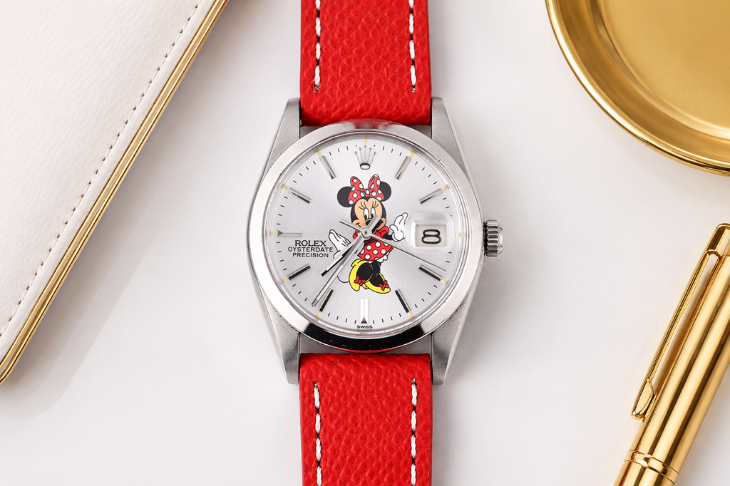 Watch with a red strap featuring a cartoon character on a white surface with gold accents.