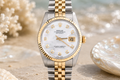 Luxury watch with a gold and silver band on a beach setting