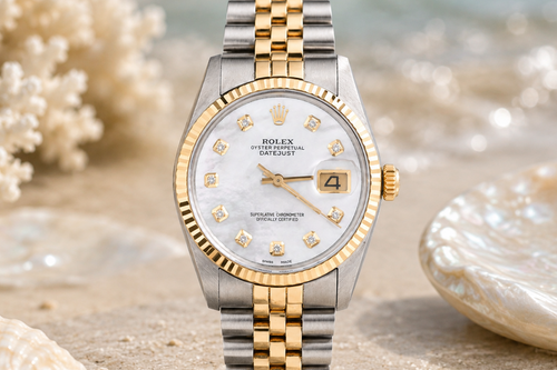 Luxury watch with a gold and silver band on a beach setting