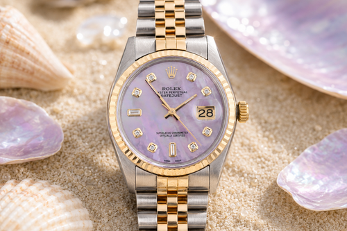 Luxury watch with a two-tone band on sand with seashells