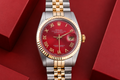 Luxury watch with red face and gold accents on a red background