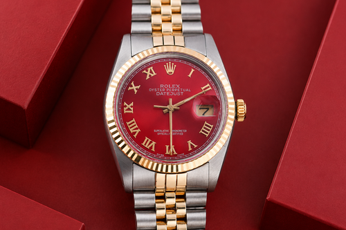 Luxury watch with red face and gold accents on a red background