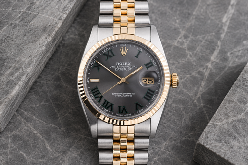Rolex watch with two-tone gold and silver bracelet on a gray stone surface