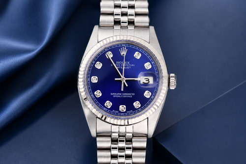 Silver watch with a blue dial on a dark blue fabric background