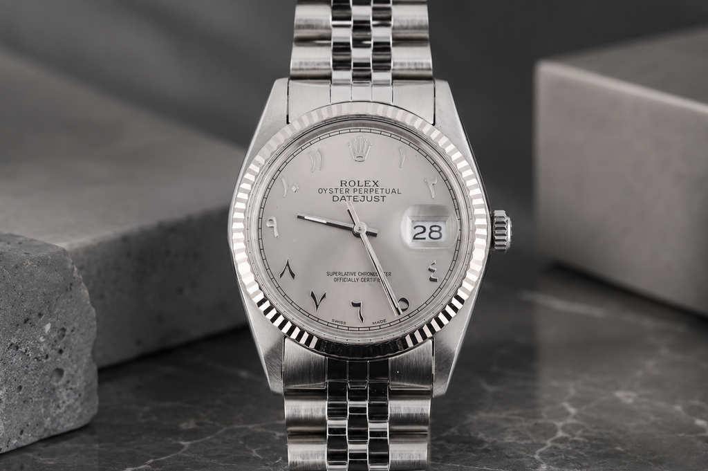 Silver Rolex watch on a dark surface with a gray background