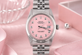 Silver watch with a pink face on a pink background