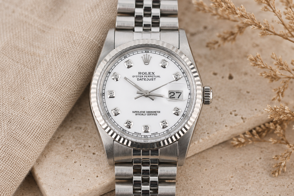 Silver watch with a white face on a beige fabric background