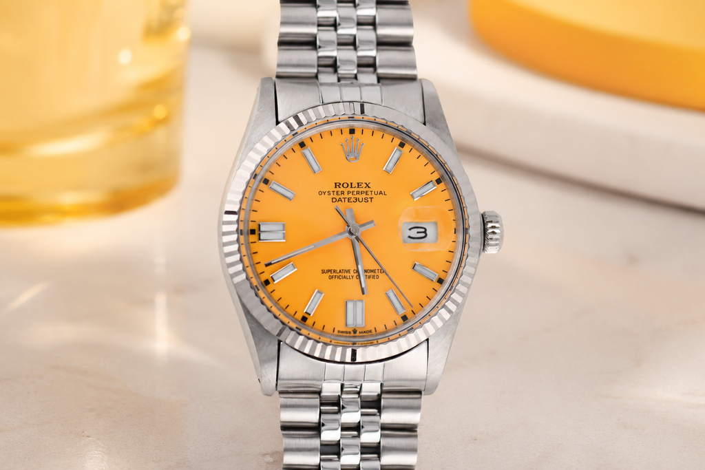 Silver watch with a bright orange face on a light background