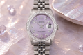 Silver watch with a purple face on a textured surface