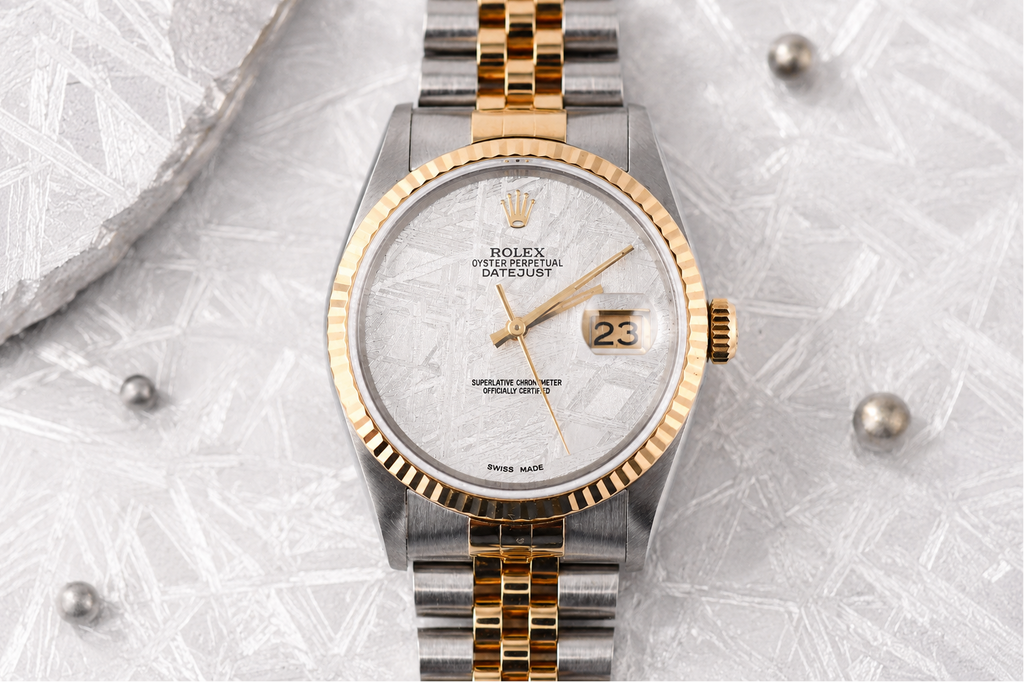 Luxury watch with gold and silver band on a textured gray background