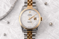 Luxury watch with gold and silver band on a textured gray background