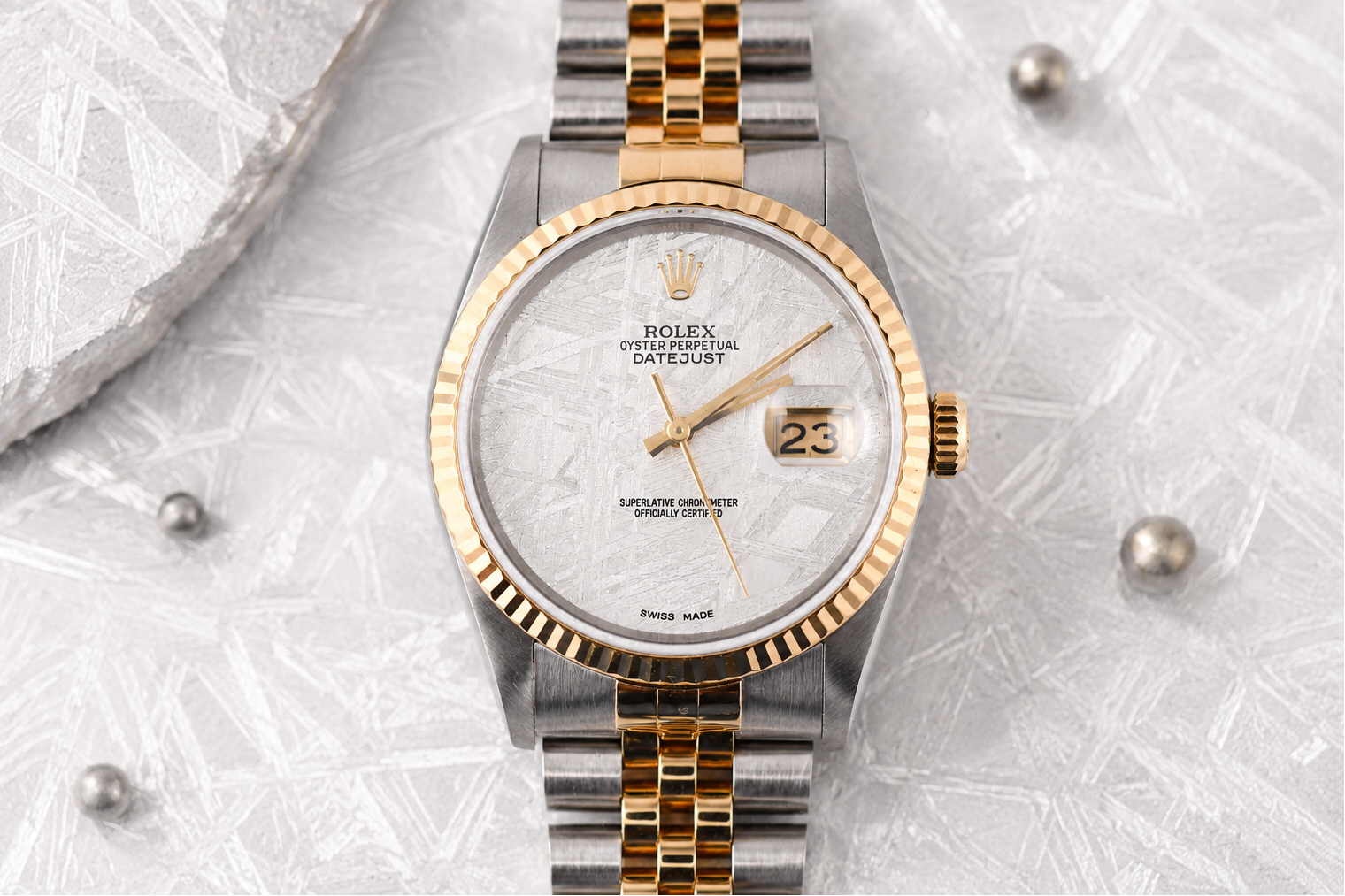 Luxury watch with gold and silver band on a textured gray background
