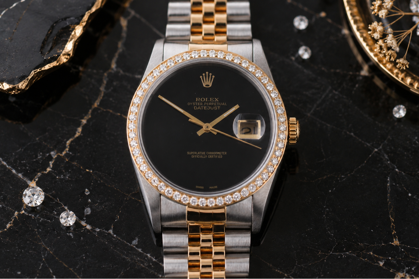 Luxury watch with black dial and diamond-studded bezel on a dark marble surface.