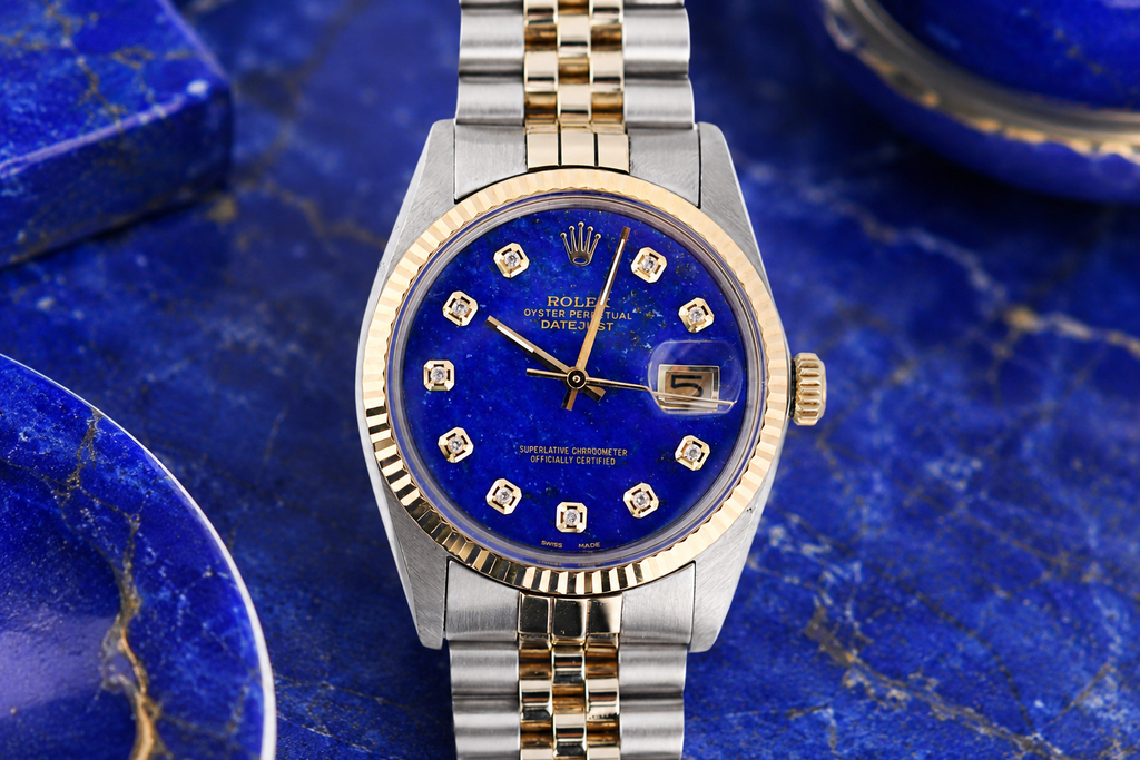 Rolex watch with blue dial and gold accents on a blue marble background