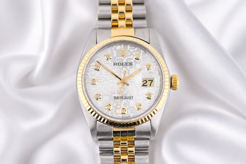Two-tone Rolex watch with silver and gold band on a white fabric background