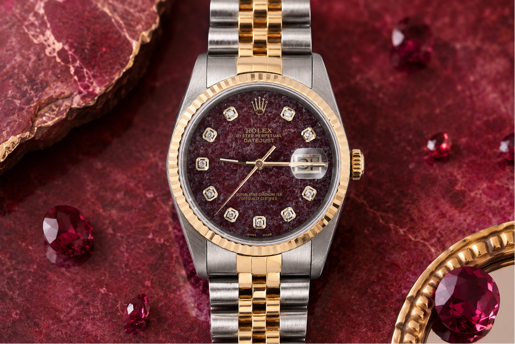 Luxury watch with a maroon face and gold accents on a red textured background with gemstones.