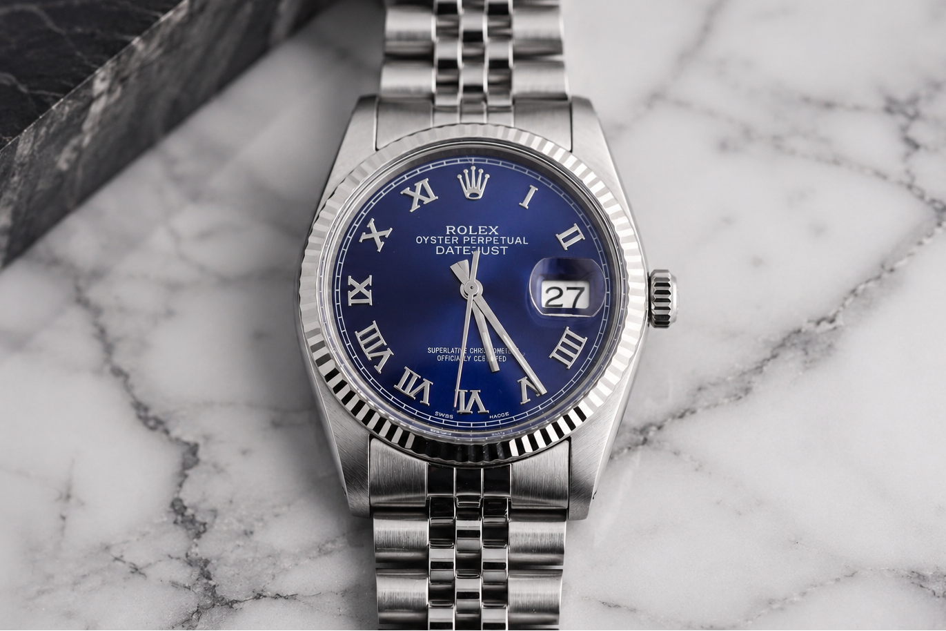 Silver watch with a blue face on a marble surface