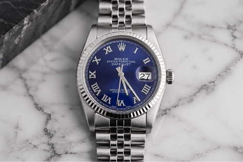 Silver watch with a blue face on a marble surface
