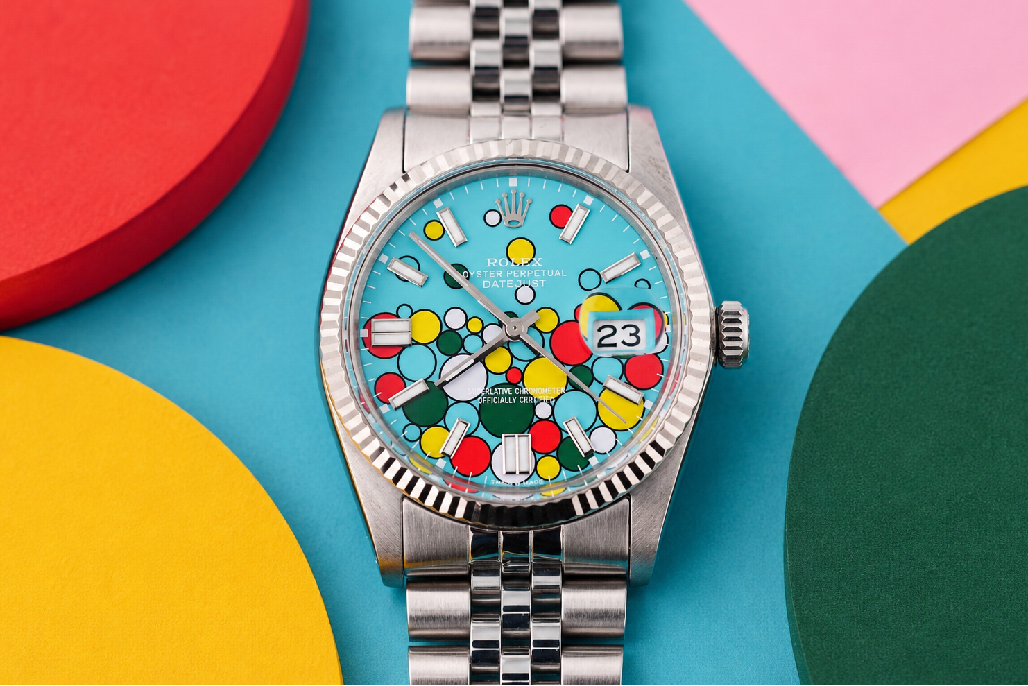 Silver watch with a colorful face on a multicolored geometric background