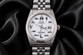 Silver watch with a unique face design on a black satin background