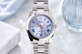 Silver watch with a blue face on a white marble surface