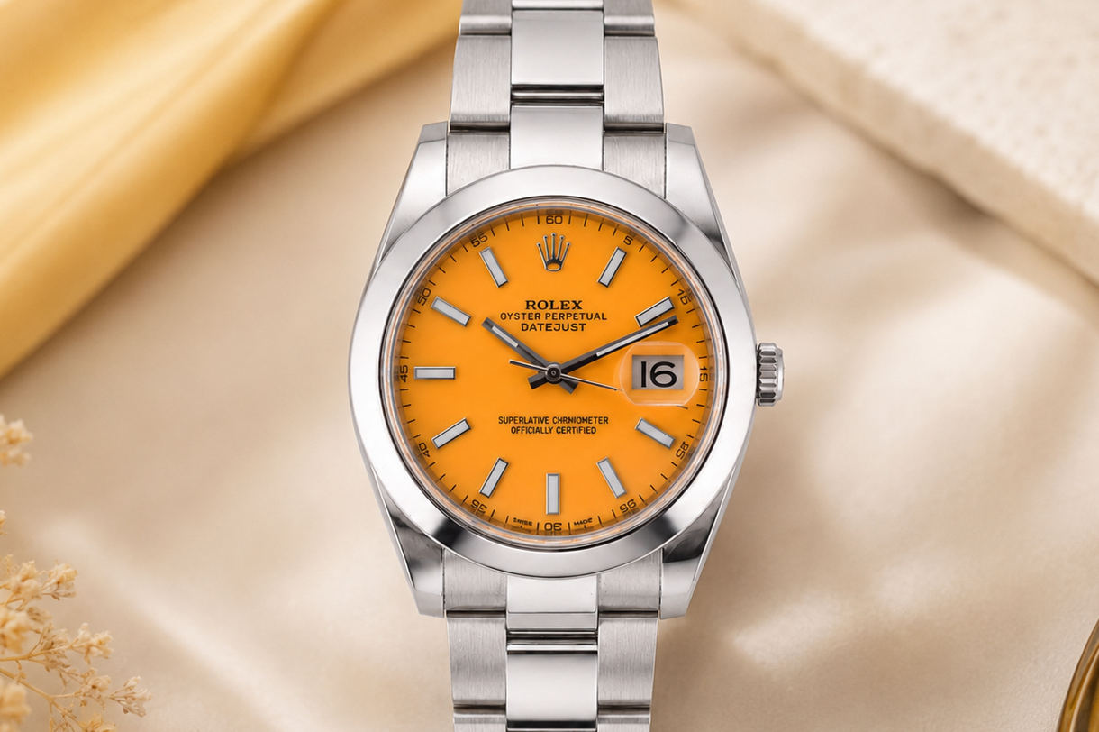 Silver watch with orange face on a beige surface with flowers