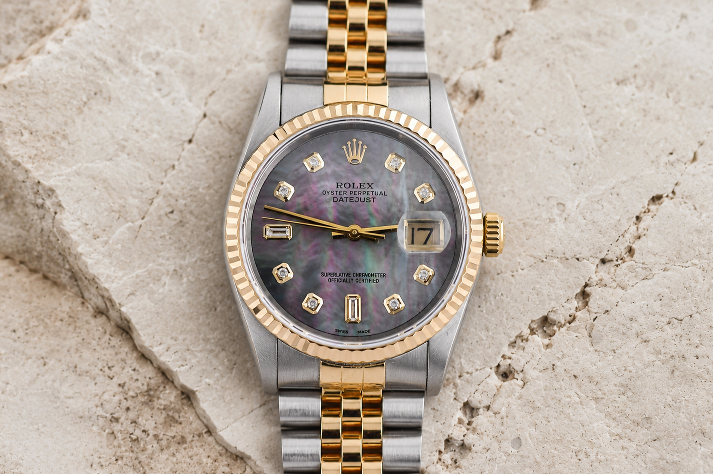 Luxury watch with a two-tone gold and silver band on a textured stone surface