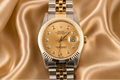 Luxury Rolex watch with gold and silver band on a satin background