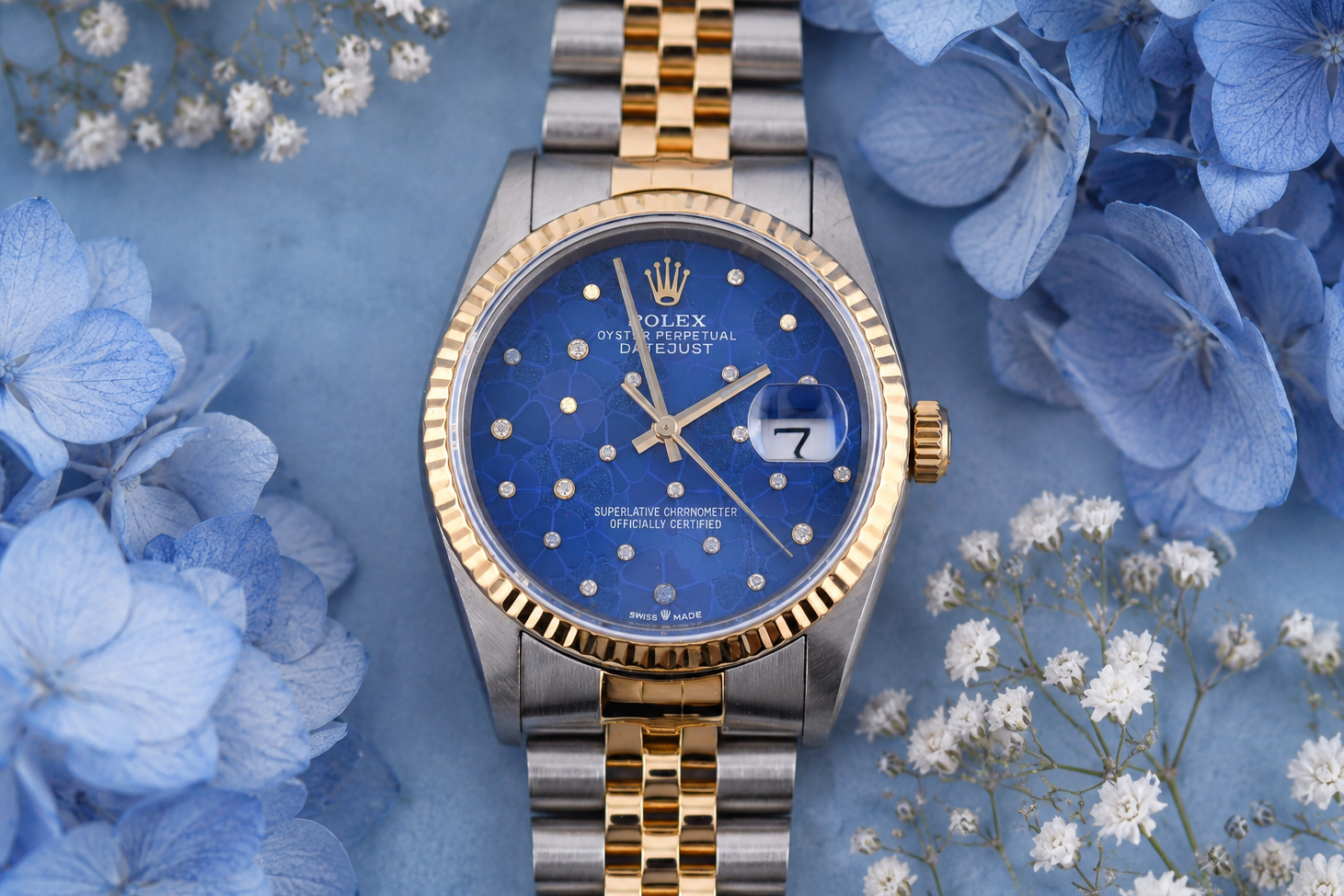 Luxury watch with blue dial and gold accents on a floral background