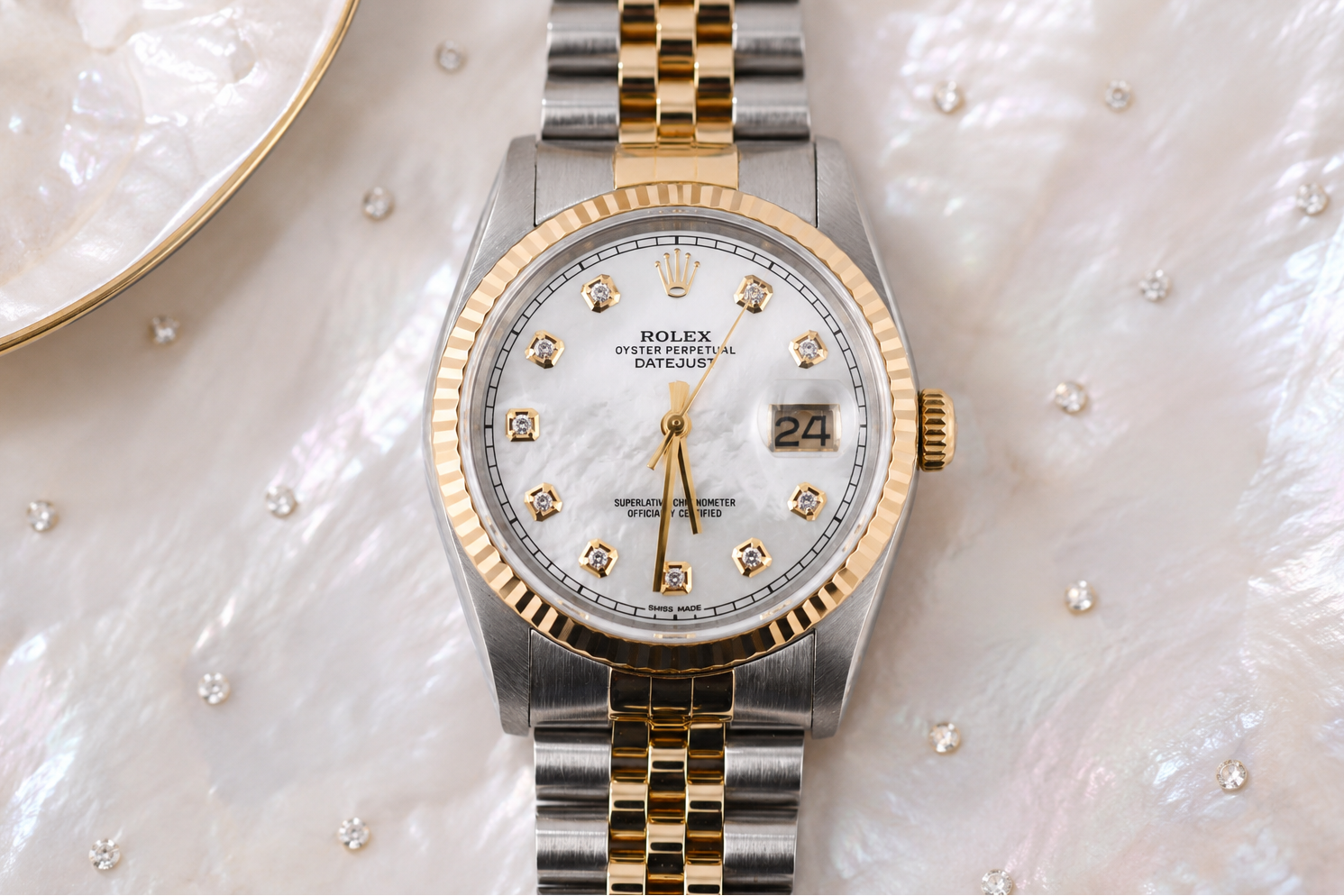 Rolex watch with silver and gold band on a textured white surface