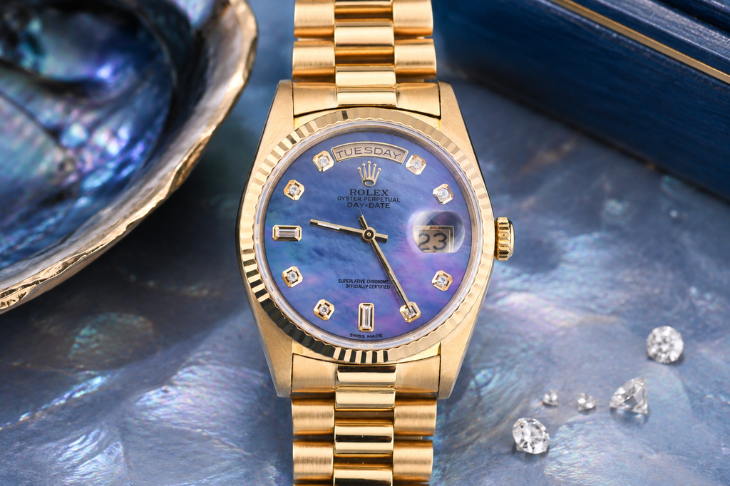 Gold watch with a blue face on a textured surface with diamonds and a shell.