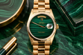 Gold watch with green face on a green marble surface