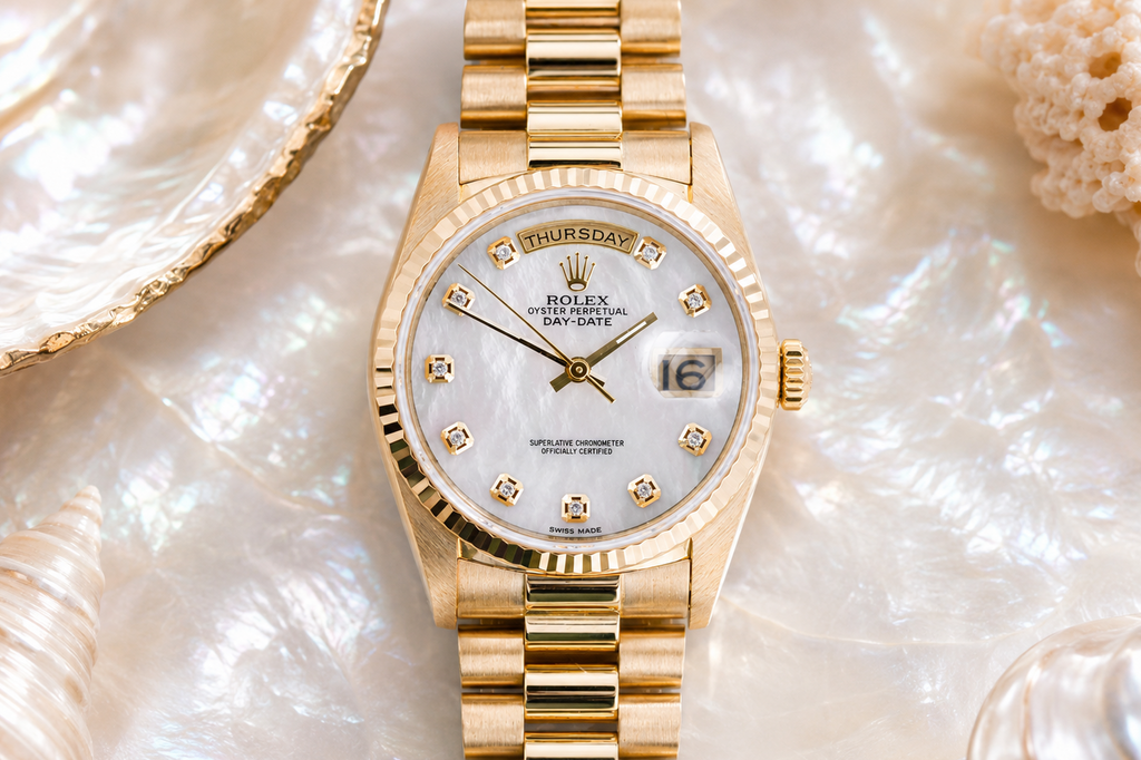 Gold watch with a white face on a textured shell background